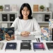 Woman Smiling With Many Notebooks On Desk