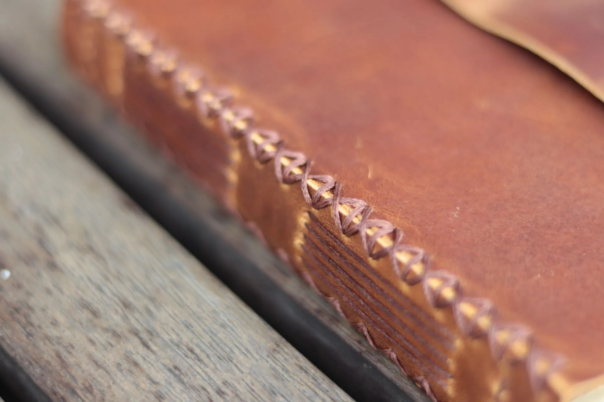 Tampilan close-up dari tulang punggung Jurnal Baklava, menunjukkan detail jahitan longstitch dan pola silang 'X' yang rumit.