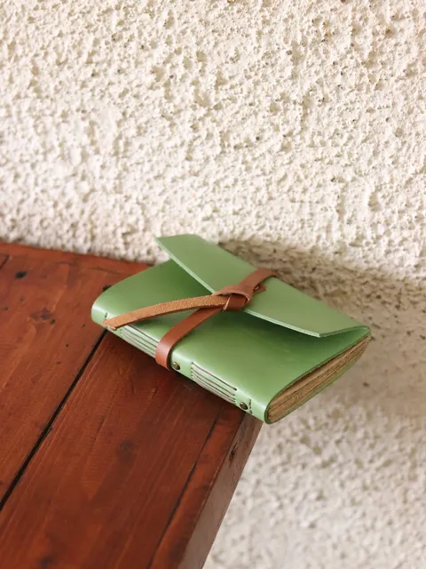 Buku catatan kulit hijau mint dengan penutup kustom, menunjukkan contoh produk Hibrkraft