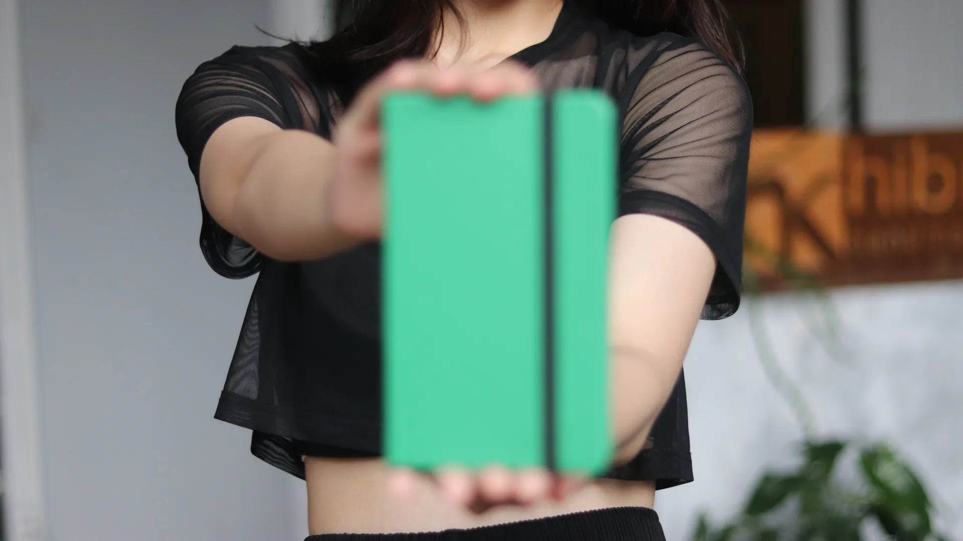 Seorang wanita menampilkan jurnal berwarna hijau cerah ke arah kamera, menunjukkan bagaimana desain yang tahan lama bisa tetap modern dan penuh gaya.