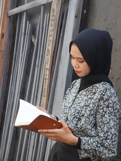 Wanita membaca jurnal kulit coklat, menunjukkan penggunaan personal dan profesional.